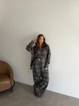 Camisa de viyela con estampado de cuadros en tonos marrones, beige y negro. Presenta cuello clásico, cierre frontal con botones, mangas largas con puños abotonados y dos bolsillos delanteros con solapa.