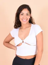 Blusa blanca de punto canalé con escote en pico y abertura en el abdomen unida por un aro metálico.