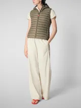 Chaleco acolchado ligero color gris topo, con capucha y cierre frontal. Confeccionado con relleno sintético Plumtech.