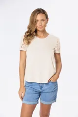 Remera de algodón color beige con cuello redondo y mangas cortas que presentan detalles calados en broderie.