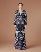 Vestido largo de gasa con estampado abstracto en tonos blanco y negro. Presenta escote en V profundo, mangas largas con volumen en los hombros y puños fruncidos, y aberturas laterales en la cintura.