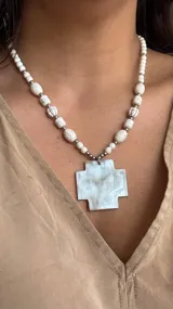 Collar con cuentas de piedra blanca y dije de cruz.