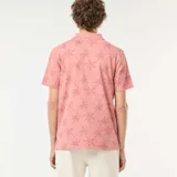 Remera polo rosada de piqué con estampado de palmeras.