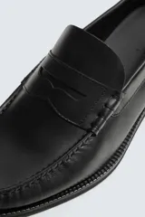 Mocasín de vestir fabricado en piel color marrón oscuro, con detalle de antifaz en el empeine, plantilla de piel y suela a contraste con ligero tacón.