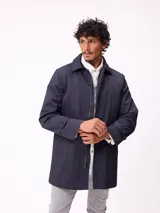 Gabardina de corte clásico en color azul marino, con cierre frontal de botones y cremallera oculta, cuello camisero y puños ajustables con botones.
