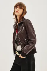 Campera estilo biker color ciruela, con múltiples cierres metálicos decorativos en el frente y mangas. Tiene cuello alto con broches, puños y cintura elastizados.