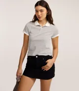 Minifalda de jeans negra, de tiro alto, con cierre tradicional y trabillas en la cintura. Presenta detalles de tachuelas metálicas en los bolsillos delanteros.