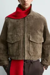 Cazadora de corte boxy fit confeccionada en piel con acabado de ante. Presenta cuello solapa, cierre frontal con cremallera, mangas largas con puños ajustables mediante botón a presión oculto y dos bolsillos de plastrón con solapa en la parte frontal.
