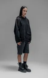 Hoodie oversize color negro, confeccionado en frisa gamuzada de algodón. Presenta capucha forrada en microfibra, mangas raglán y un bolsillo frontal tipo canguro con un bolsillo pequeño superpuesto con solapa.