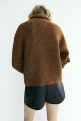 Jersey de punto con textura, cuello subido y manga larga, de corte recto y diseño clásico.