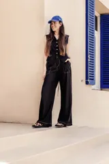 Pantalón negro de lino con tiro medio, elástico en la cintura trasera, bolsillos delanteros carpinteros en contraste blanco y botón marmolado.