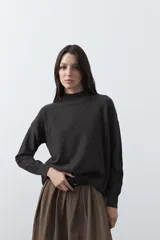 Polera de tejido de punto color gris oscuro, con cuello alto y diseño de rombos en relieve en el frente. Presenta un calce relajado con terminaciones en rib en cuello, puños y ruedo.