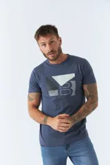 Remera de hombre color azul, con cuello redondo y manga corta. Presenta un diseño gráfico estampado en el frente con formas geométricas y letras en tonos blanco y gris.