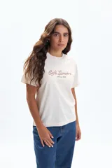 Remera de manga corta color crudo con estampado frontal que dice "Café Lumière" en cursiva y "Open All Week" debajo.