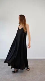 Vestido largo de satén negro, con diseño de solera, escote en V y breteles finos ajustables. Presenta un corte holgado y fluido.