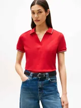 Chomba roja de algodón elástico con corte slim, cuello en V, tapeta abierta y mangas cortas con ribetes blancos y azul marino. Logo de Tommy Hilfiger bordado en el pecho.