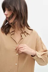 Camisa color beige de corte clásico, con cuello y mangas largas.