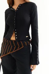 Top de manga larga color amarillo, confeccionado en tejido acanalado con cierre frontal de botones a presión metálicos. Presenta detalles de botones en los puños y un corte ajustado al cuerpo.