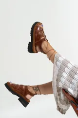 Sandalias de cuero color marrón con textura de cocodrilo, plataforma con suela track y tiras finas que se atan al tobillo.