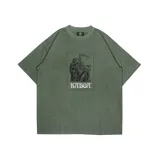 Remera verde militar de corte oversize con estampa rectangular en el frente que incluye dos figuras encapuchadas y la inscripción "KABOK".