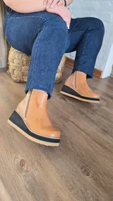 Botinetas de cuero color suela, con diseño de caña baja, doble cierre lateral, talón con textura animal print estilo reptil y suela de plataforma corrida bicolor en negro y suela.