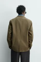 Blazer regular fit de Zara Origins, confeccionada en tejido de lana y algodón color verde militar. Presenta cuello con solapas de muesca, cierre frontal de un botón, bolsillos de solapa en la cadera y bolsillo de vivo en el pecho.