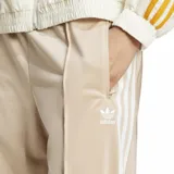 Pantalón deportivo Adidas modelo Firebird de corte holgado y pierna ancha. Presenta cintura elástica, bolsillos laterales con cierre y las icónicas tres tiras de la marca en los laterales. Incluye el logo del trébol bordado en la parte superior.