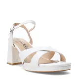 Sandalias Miss Carol Caletta de color blanco, con tiras cruzadas en el empeine, plataforma delantera, taco ancho y tira al tobillo con cierre de hebilla metálica.