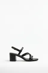 Sandalias de tacón medio y cuadrado, color negro con textura efecto cocodrilo, tiras finas cruzadas en el empeine y tira ajustable con hebilla en el tobillo.