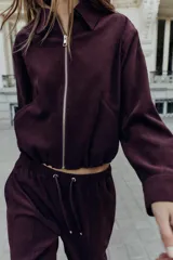 Cazadora bomber de Zara, de color bordó, con cuello de solapa, manga larga, bolsillos de vivo en el delantero y bajo elástico. Cuenta con cierre frontal de cremallera metálica.