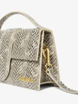 Bolso estructurado con estampado de piel de serpiente en tonos beige y negro, con asa superior acolchada y correa larga extraíble. Cierre magnético con solapa y herrajes metálicos dorados.