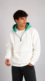 Hoodie de color blanco con cierre frontal parcial, capucha en color verde menta y bolsillo frontal tipo canguro. Presenta un pequeño logo bordado en el pecho.