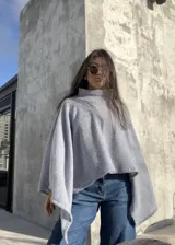 Poncho de hilo liviano en color gris claro, con cuello alto y diseño de caída fluida y holgada. Es una prenda versátil ideal para media estación.