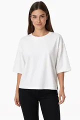 Remera de algodón color blanco, de corte holgado y diseño minimalista con cuello redondo y mangas cortas amplias.