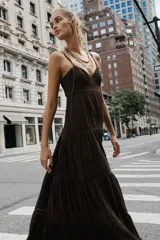 Vestido largo color marrón, de escote en pico y tirantes finos ajustables. Cuenta con diseño de volantes escalonados unidos por entredoses a tono, abertura en la espalda con elástico y forro interior.