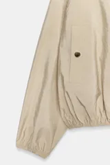 Cazadora tipo bomber de cuello redondo y manga larga con puños elásticos. Presenta cierre frontal con cremallera metálica, bolsillos laterales de vivo con botón a presión y bajo con ajuste elástico.