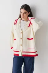 Cardigan de punto color chocolate con diseño de bloques de color y detalles a rayas en cuello, puños y ruedo. Presenta cierre frontal con botones, cuello tipo polo y dos bolsillos delanteros.