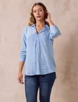 Camisa celeste de lyocell con cuello con solapa, escote en V y cierre con botones. Presenta un bolsillo en el pecho y mangas 3/4 con puño abotonado.