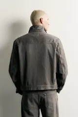 Cazadora de denim de algodón en color gris oscuro con efecto lavado, corte relaxed fit, cuello camisero, bolsillos delanteros con solapa en el pecho y cierre frontal con botones.