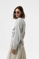 Chaqueta de calce relajado y estilo utilitario, color gris, con bolsillos delanteros grandes con solapa y cinturón ajustable en la cintura.