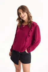 Blusa de viscosa color blanco con escote en V y cordón ajustable, mangas largas y volados decorativos en los hombros.
