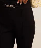 Pantalón flare negro de punto roma con detalle metálico en la cintura y cierre delantero.