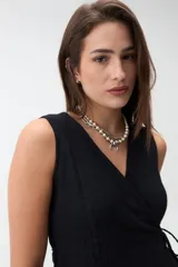 Chaleco cruzado negro sin mangas con escote en V y lazo de ajuste lateral, confeccionado en tejido texturado.