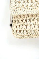 Bandolera beige de tejido rústico estilo crochet con solapa, correa larga con cuentas de madera decorativas y cierre superior.
