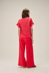 Blusa de lino color rosado, de corte recto y holgado, con cuello redondo y mangas cortas adornadas con volados.