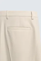 Pantalón de corte recto confeccionado en tejido con lana, color beige. Presenta bolsillos frontales, bolsillos traseros de vivo y cierre frontal con cremallera y botón.