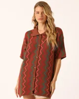 Vestido corto marrón con diseño de zig zag en verde y naranja, cuello tipo polo y cierre delantero con botones.