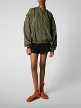 Campera bomber verde militar, con cierre frontal, cuello, puños y cintura elásticos. Presenta bolsillos con cierre en las mangas y un bolsillo lateral con cierre.