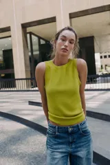 Top de punto color amarillo mostaza, con cuello redondo y manga sisa. Acabados en rib a tono.