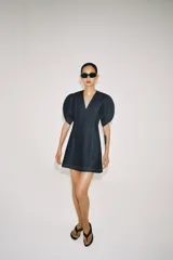 Vestido corto de denim con escote en pico, mangas cortas abullonadas con aberturas y costuras con pespuntes a contraste. Cierre posterior con cremallera.